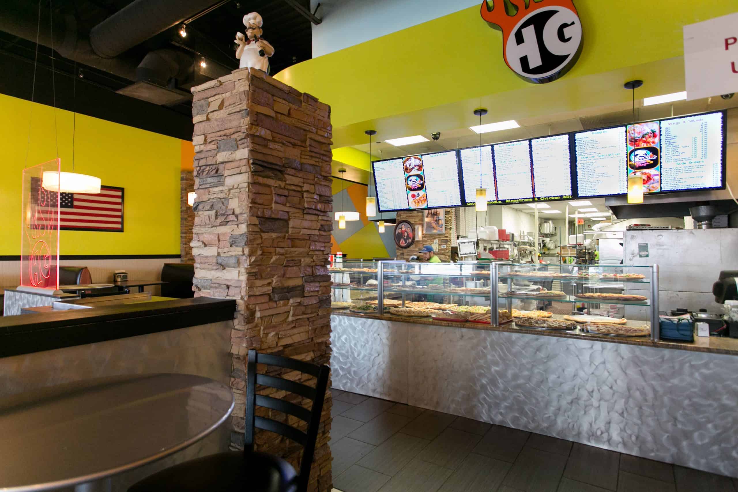 Inside Pizza Plaza of Warminster, with a fresh pizza counter and warm dining area